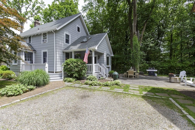 102 Rose Ln, Darien, CT 06820 - view of front of home featuring a shingled roof, a patio area, a chimney, and an outdoor fire pit