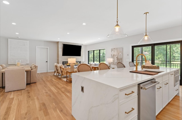 10 Singing Woods Rd, Norwalk, CT 06850 - kitchen with open floor plan, white cabinetry, a kitchen island with sink, light wood-style floors, and hanging light fixtures