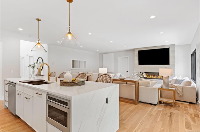 10 Singing Woods Rd, Norwalk, CT 06850 - kitchen featuring appliances with stainless steel finishes, white cabinets, a center island with sink, light wood-style floors, and open floor plan