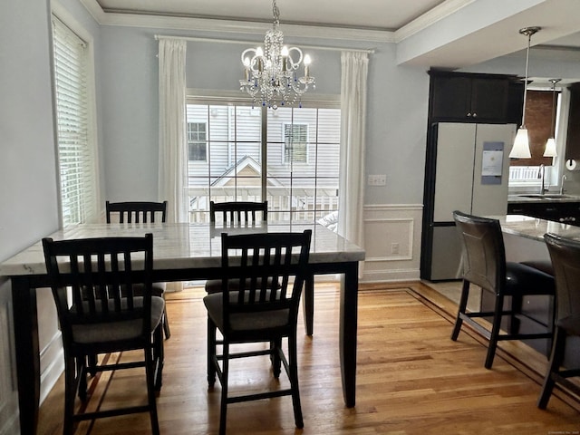 40 Ferris Ave Apt 6, Norwalk, CT 06854 - dining area featuring a chandelier, a wainscoted wall, light wood finished floors, crown molding, and a decorative wall