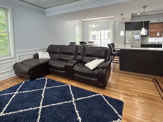 40 Ferris Ave Apt 6, Norwalk, CT 06854 - living room with light wood finished floors, a chandelier, ornamental molding, plenty of natural light, and a wainscoted wall