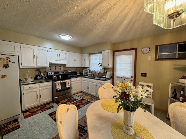 82 Louisiana Ave, Bridgeport, CT 06610 - kitchen featuring stainless steel appliances, under cabinet range hood, white cabinets, dark countertops, and a textured ceiling