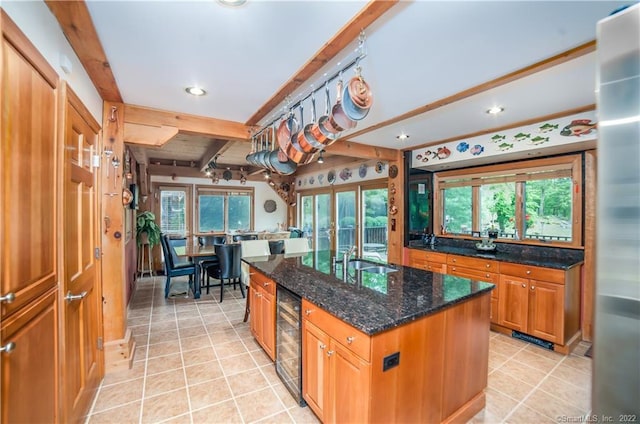 9A Obtuse Rocks Rd, Brookfield, CT 06804 - kitchen featuring wine cooler, light tile patterned floors, a center island with sink, beam ceiling, and dark stone countertops
