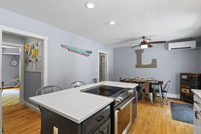 114 Dean Rd, East Lyme, CT 06333 - kitchen featuring stainless steel range with electric stovetop, a wall unit AC, baseboard heating, a ceiling fan, and light wood-style floors