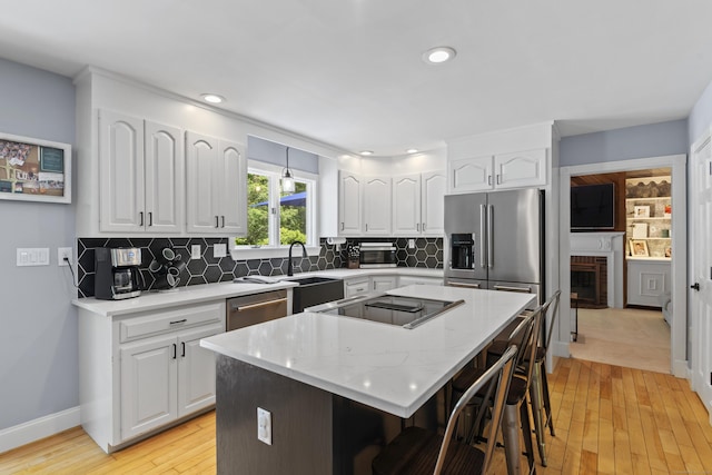 114 Dean Rd, East Lyme, CT 06333 - kitchen with stainless steel appliances, light wood-style flooring, white cabinets, a kitchen breakfast bar, and a center island