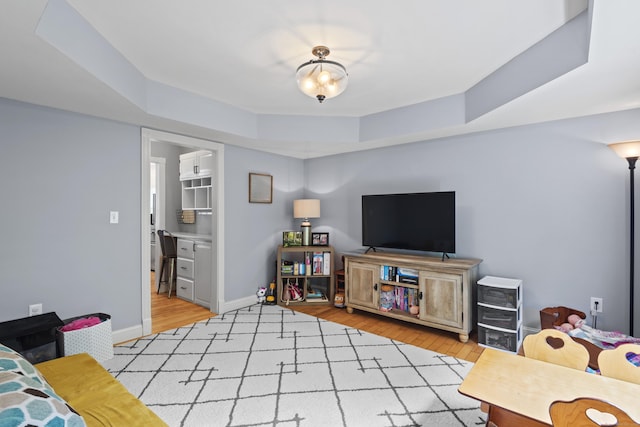 114 Dean Rd, East Lyme, CT 06333 - living room featuring a tray ceiling, light wood finished floors, and baseboards