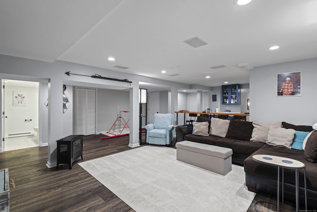 114 Dean Rd, East Lyme, CT 06333 - living area with dark wood-type flooring, a baseboard heating unit, a wood stove, bar, and baseboards