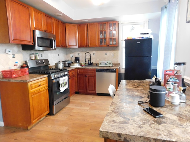 157 Madison Ter, Bridgeport, CT 06606 - kitchen featuring stainless steel appliances, light wood finished floors, brown cabinets, decorative backsplash, and a sink
