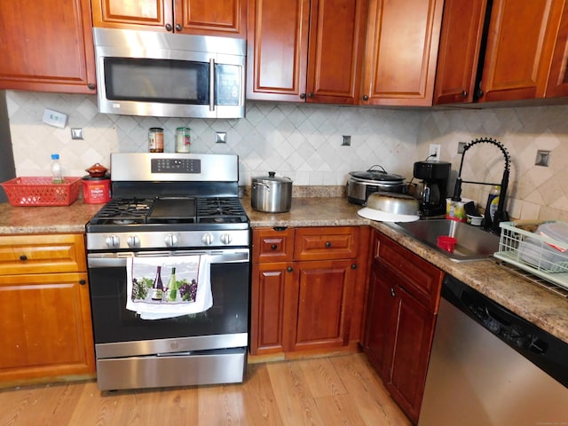 157 Madison Ter, Bridgeport, CT 06606 - kitchen featuring stainless steel appliances, a sink, backsplash, light wood-style floors, and brown cabinets