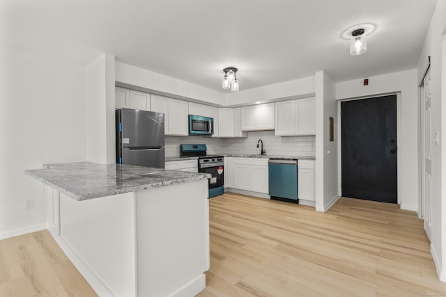 79 Claudia Dr Apt 254, West Haven, CT 06516 - kitchen with stainless steel appliances, a peninsula, light stone countertops, backsplash, and light wood-type flooring