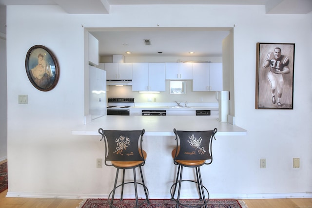26 Cove Ave Apt 3B, Norwalk, CT 06855 - kitchen featuring white range with electric stovetop, a peninsula, a breakfast bar area, light wood-style flooring, and under cabinet range hood