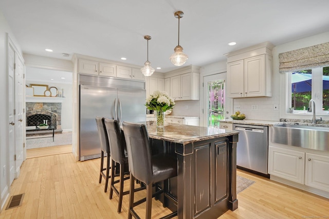 15 Stony Cors, Avon, CT 06001 - kitchen featuring stainless steel appliances, a sink, a center island, light stone counters, and light wood-style flooring