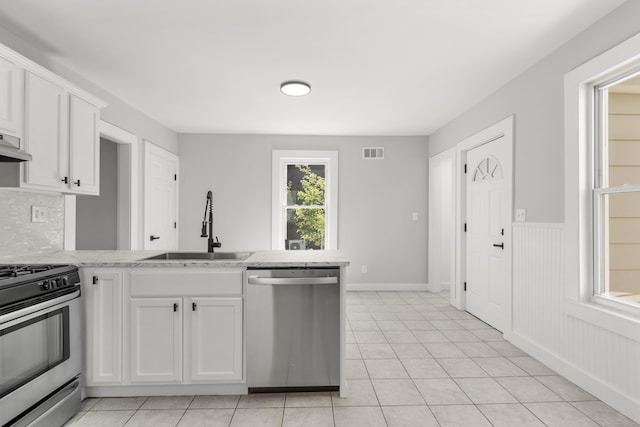 17 May St, Ansonia, CT 06401 - kitchen featuring appliances with stainless steel finishes, a sink, white cabinets, light tile patterned floors, and a wainscoted wall