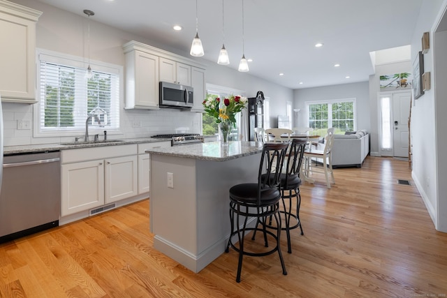 100 Silver Island Way Unit 100, Berlin, CT 06037 - kitchen with appliances with stainless steel finishes, a sink, backsplash, light wood-style floors, and a kitchen island