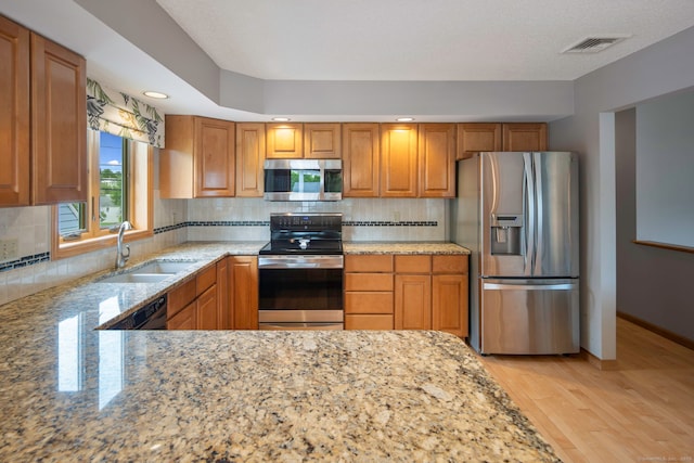 8 Lindsley St, Waterbury, CT 06708 - kitchen with appliances with stainless steel finishes, a sink, light stone counters, light wood finished floors, and brown cabinets