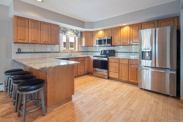 8 Lindsley St, Waterbury, CT 06708 - kitchen with stainless steel appliances, a peninsula, brown cabinetry, light stone counters, and recessed lighting