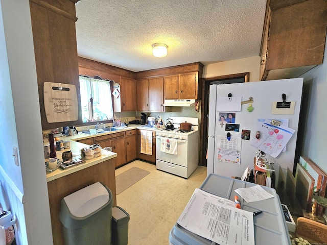 100 Morin Ave, Killingly, CT 06239 - kitchen with white appliances, under cabinet range hood, brown cabinets, light countertops, and light floors