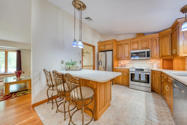 169 Dunn Rd, Coventry, CT 06238 - kitchen featuring stainless steel appliances, light countertops, backsplash, a kitchen bar, and decorative light fixtures