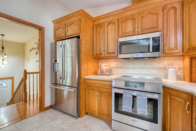 169 Dunn Rd, Coventry, CT 06238 - kitchen featuring stainless steel appliances, light countertops, decorative backsplash, and brown cabinetry