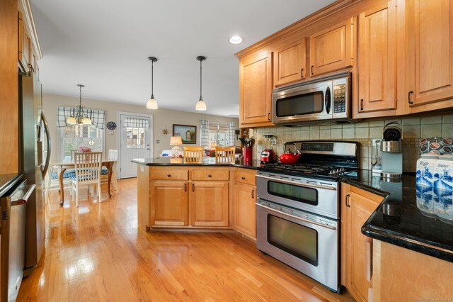 26 Parkway S, New London, CT 06320 - kitchen featuring appliances with stainless steel finishes, a peninsula, light wood-type flooring, tasteful backsplash, and decorative light fixtures