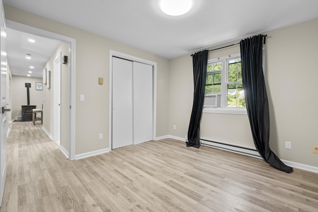 13 Williams Ct, Wolcott, CT 06716 - unfurnished bedroom featuring light wood-style flooring, a baseboard heating unit, a wood stove, and baseboards