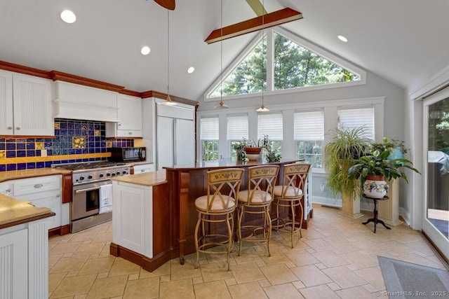 132 Old N Stamford Rd, Stamford, CT 06905 - kitchen featuring high end appliances, a center island, tasteful backsplash, white cabinets, and stone tile flooring
