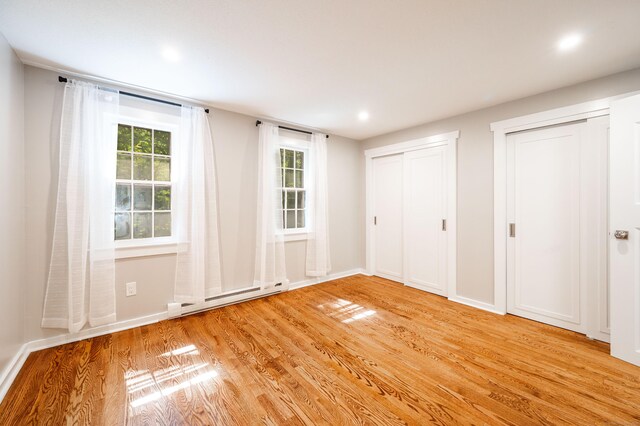 239 Old Farms Rd Apt 15B, Avon, CT 06001 - unfurnished bedroom with multiple closets, baseboard heating, light wood finished floors, baseboards, and recessed lighting