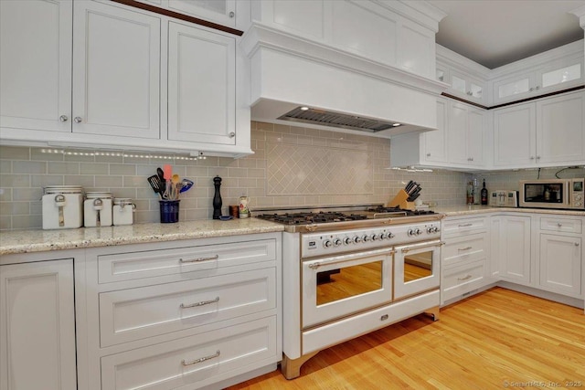 2 Lake Louise Dr, Westbrook, CT 06498 - kitchen with double oven range, built in microwave, custom range hood, white cabinets, and decorative backsplash