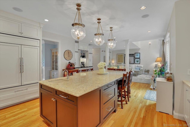 2 Lake Louise Dr, Westbrook, CT 06498 - kitchen with a sink, a breakfast bar, open floor plan, light wood-type flooring, and a chandelier