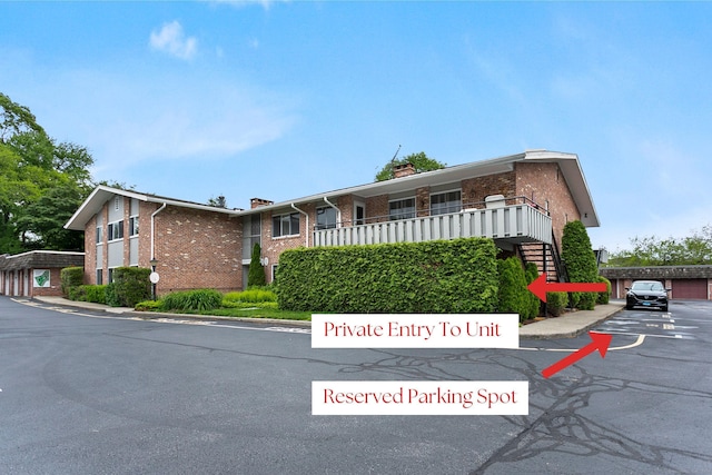 116 Southport Woods Dr, Fairfield, CT 06890 - view of front facade with brick siding, a chimney, and uncovered parking