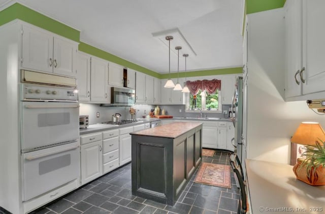 846 Arbutus St, Middletown, CT 06457 - kitchen with appliances with stainless steel finishes, light countertops, white cabinets, a kitchen island, and decorative light fixtures