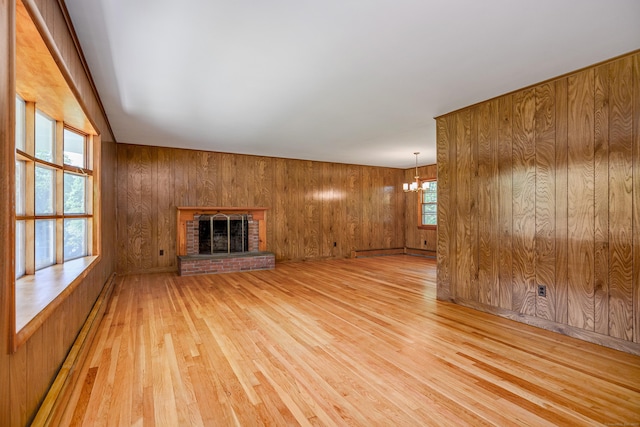 66 Hobby Dr, Ridgefield, CT 06877 - unfurnished living room featuring light wood-style flooring, a chandelier, wooden walls, and a brick fireplace
