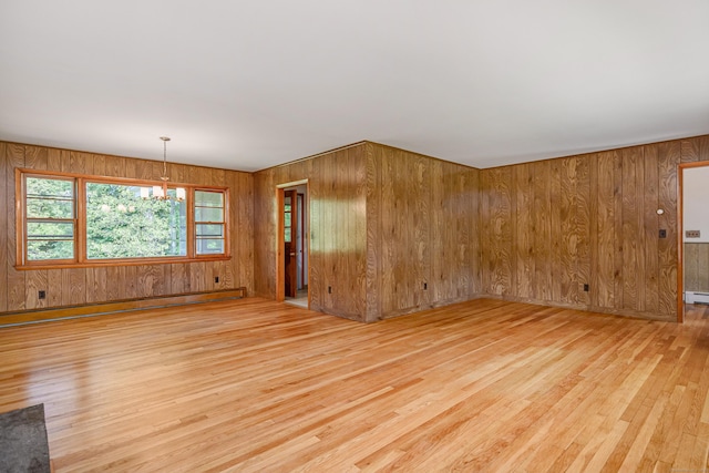 66 Hobby Dr, Ridgefield, CT 06877 - empty room with light wood-style floors, a baseboard radiator, wood walls, and a chandelier