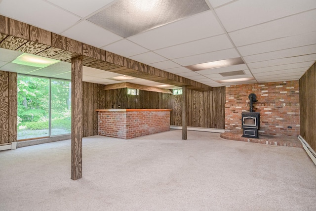 66 Hobby Dr, Ridgefield, CT 06877 - basement with a paneled ceiling, a bar, wooden walls, a wood stove, and carpet flooring