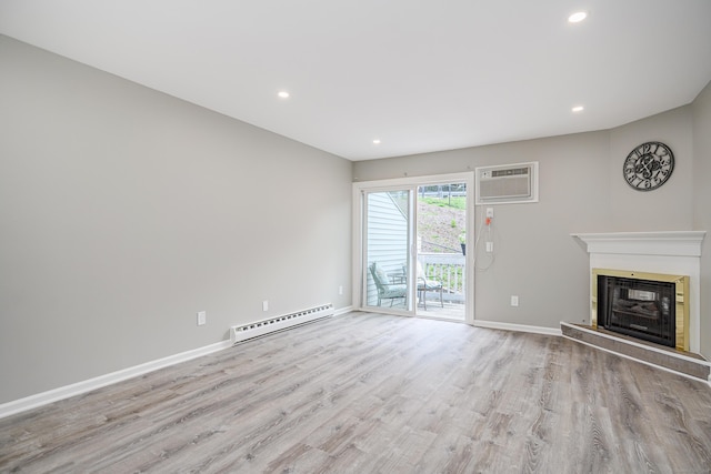 55 Mill Plain Rd Unit 34-14, Danbury, CT 06811 - unfurnished living room featuring baseboard heating, a wall mounted air conditioner, wood finished floors, a fireplace with raised hearth, and baseboards