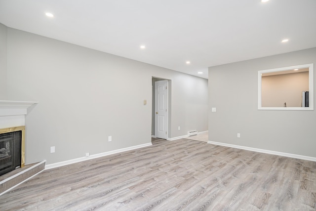 55 Mill Plain Rd Unit 34-14, Danbury, CT 06811 - unfurnished living room featuring recessed lighting, light wood finished floors, a fireplace with raised hearth, and baseboards