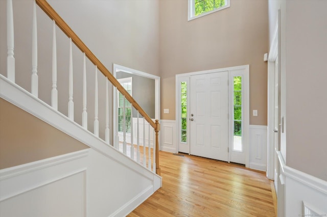 67 Bartman Rd, Haddam, CT 06441 - foyer featuring a high ceiling, stairs, a decorative wall, a wainscoted wall, and light wood-style flooring