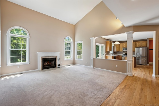 67 Bartman Rd, Haddam, CT 06441 - unfurnished living room with decorative columns, healthy amount of natural light, light wood-style floors, high vaulted ceiling, and a fireplace with flush hearth