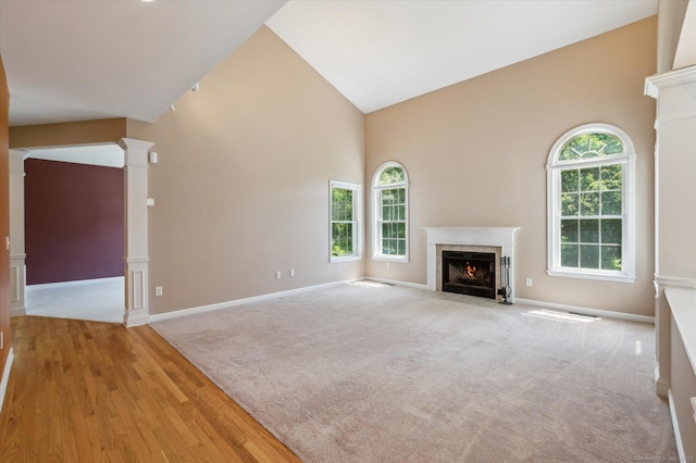 67 Bartman Rd, Haddam, CT 06441 - unfurnished living room with decorative columns, a tiled fireplace, high vaulted ceiling, baseboards, and wood finished floors