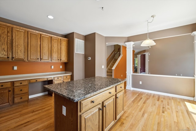 67 Bartman Rd, Haddam, CT 06441 - kitchen with light wood-type flooring, decorative columns, decorative light fixtures, brown cabinets, and a center island