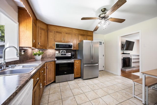 881 Pine St, Bristol, CT 06010 - kitchen with appliances with stainless steel finishes, brown cabinets, dark countertops, backsplash, and a brick fireplace