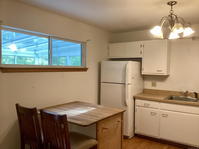 322 N St, Roxbury, CT 06783 - kitchen with a sink, freestanding refrigerator, white cabinets, a chandelier, and light wood-style flooring