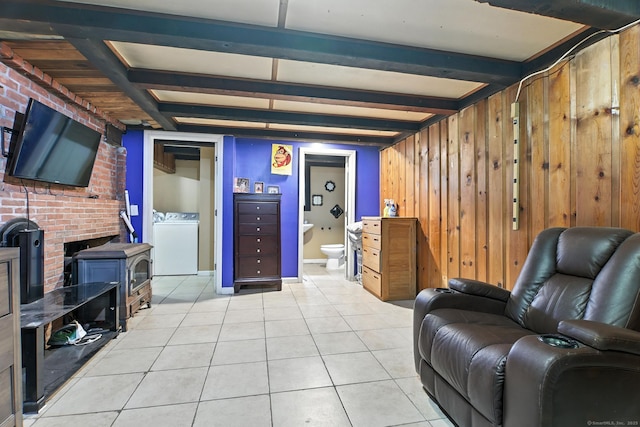 567 Bunker Hill Ave, Waterbury, CT 06708 - living area featuring light tile patterned flooring, a wood stove, wood walls, beamed ceiling, and washing machine and dryer