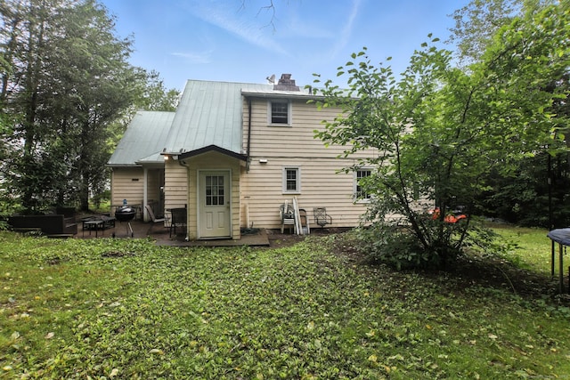 567 Bunker Hill Ave, Waterbury, CT 06708 - back of property with a patio, a chimney, a metal roof, and a lawn