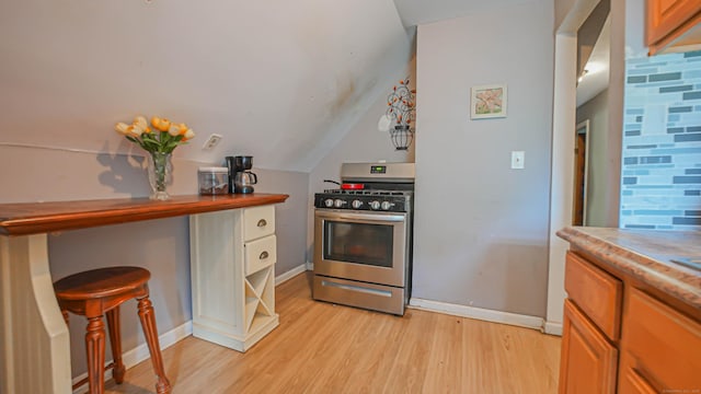 1149 Central Ave, Bridgeport, CT 06607 - kitchen with stainless steel range with gas cooktop, light wood-style floors, baseboards, lofted ceiling, and light countertops