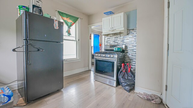 1149 Central Ave, Bridgeport, CT 06607 - kitchen featuring freestanding refrigerator, gas stove, under cabinet range hood, light wood-style flooring, and decorative backsplash