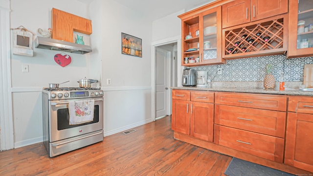1149 Central Ave, Bridgeport, CT 06607 - kitchen with gas range, under cabinet range hood, backsplash, wood finished floors, and light stone countertops