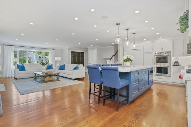25 Conrad Rd, New Canaan, CT 06840 - kitchen with stainless steel double oven, white cabinetry, blue cabinets, recessed lighting, and a breakfast bar