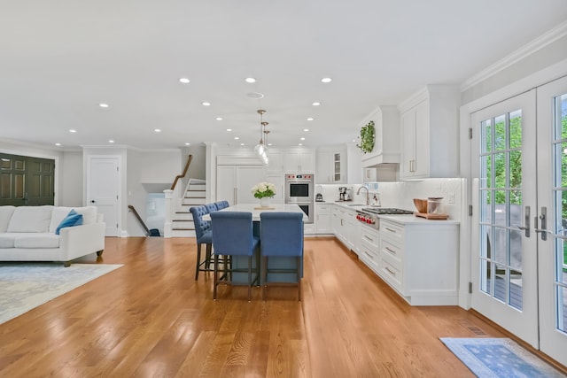 25 Conrad Rd, New Canaan, CT 06840 - kitchen featuring stainless steel appliances, french doors, a kitchen island, ornamental molding, and a kitchen bar