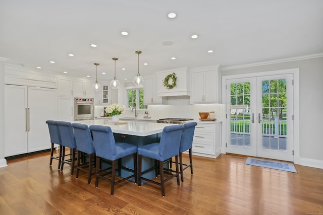 25 Conrad Rd, New Canaan, CT 06840 - kitchen with appliances with stainless steel finishes, white cabinets, light countertops, ornamental molding, and a kitchen island